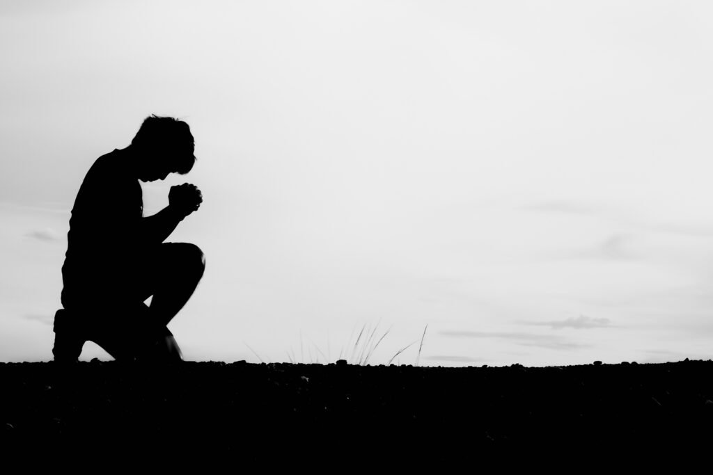Silhouette of a man sitting and praying for blessing and hope